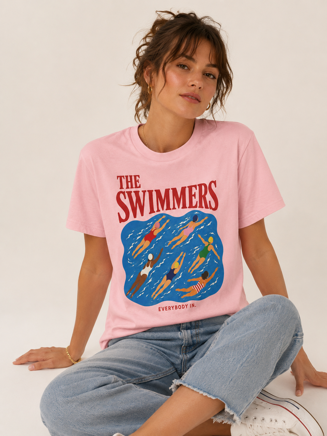 Woman styling The Swimmers pink graphic tee with jeans